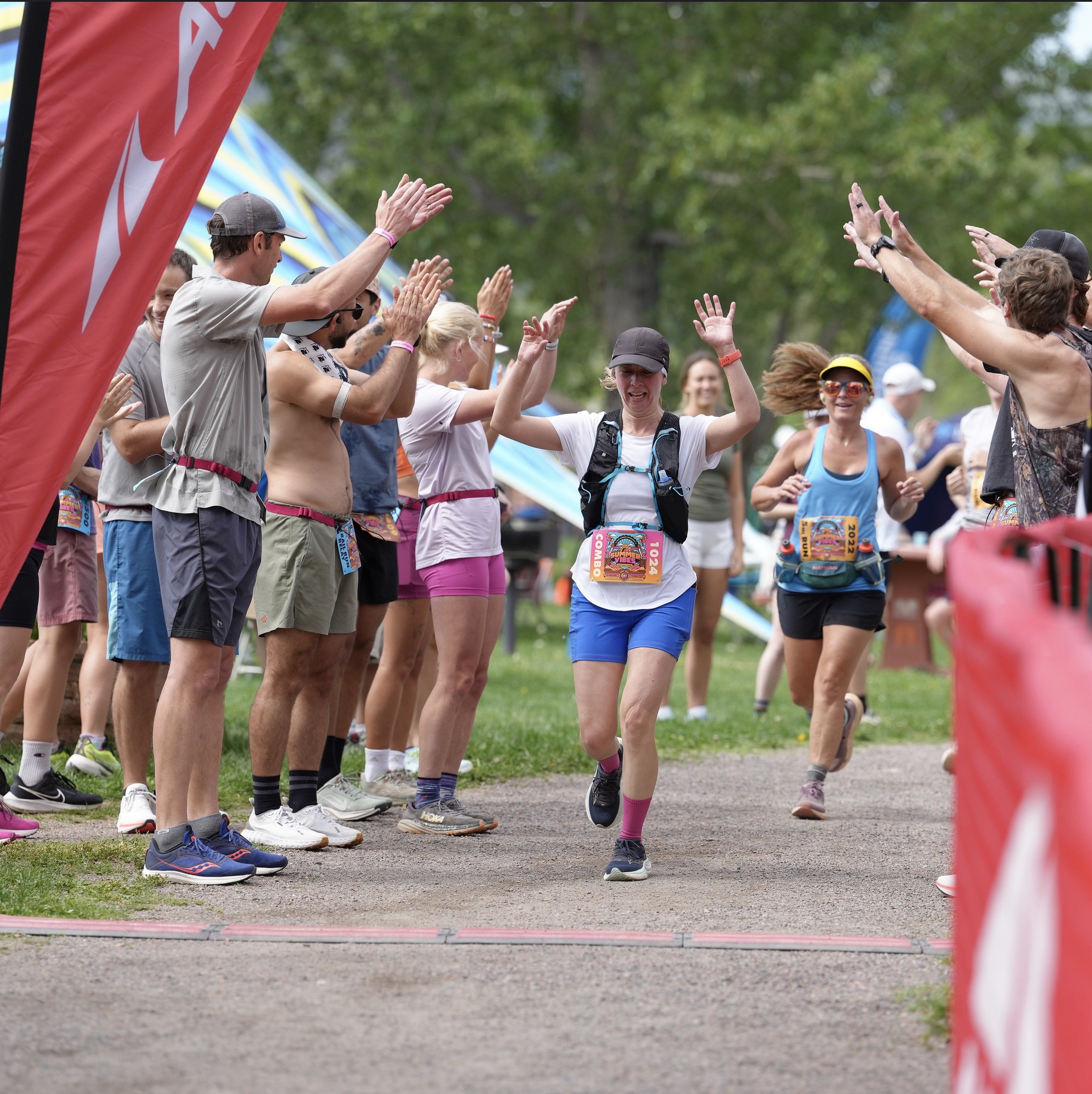 Relay runners on a grassy hillside trail